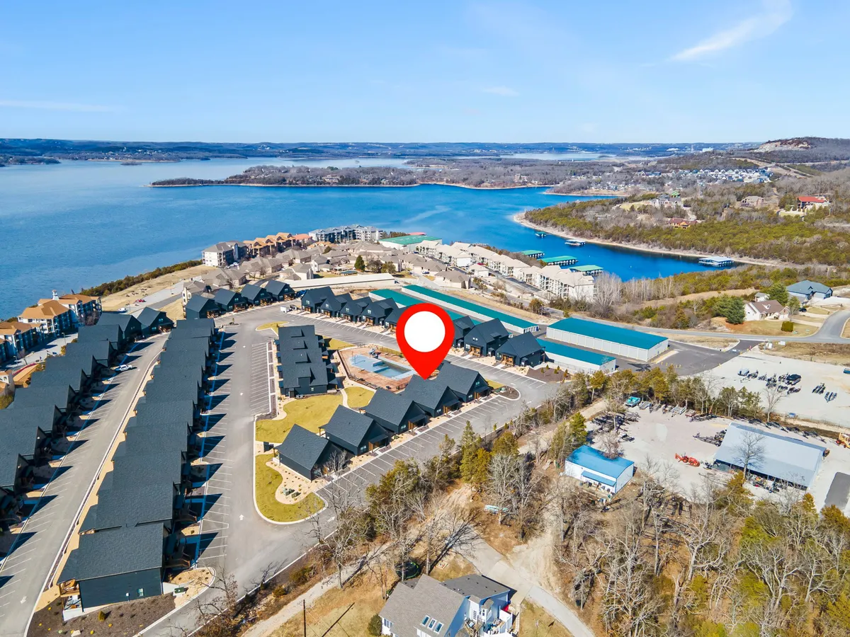 This exterior image presents a sweeping view of Table Rock Lake with residential buildings nearby, a road winding through, and the surrounding hills framing the landscape. The tranquil waters and open sky emphasize the natural beauty of the area and the proximity of the chalet to the lake and outdoor activities.