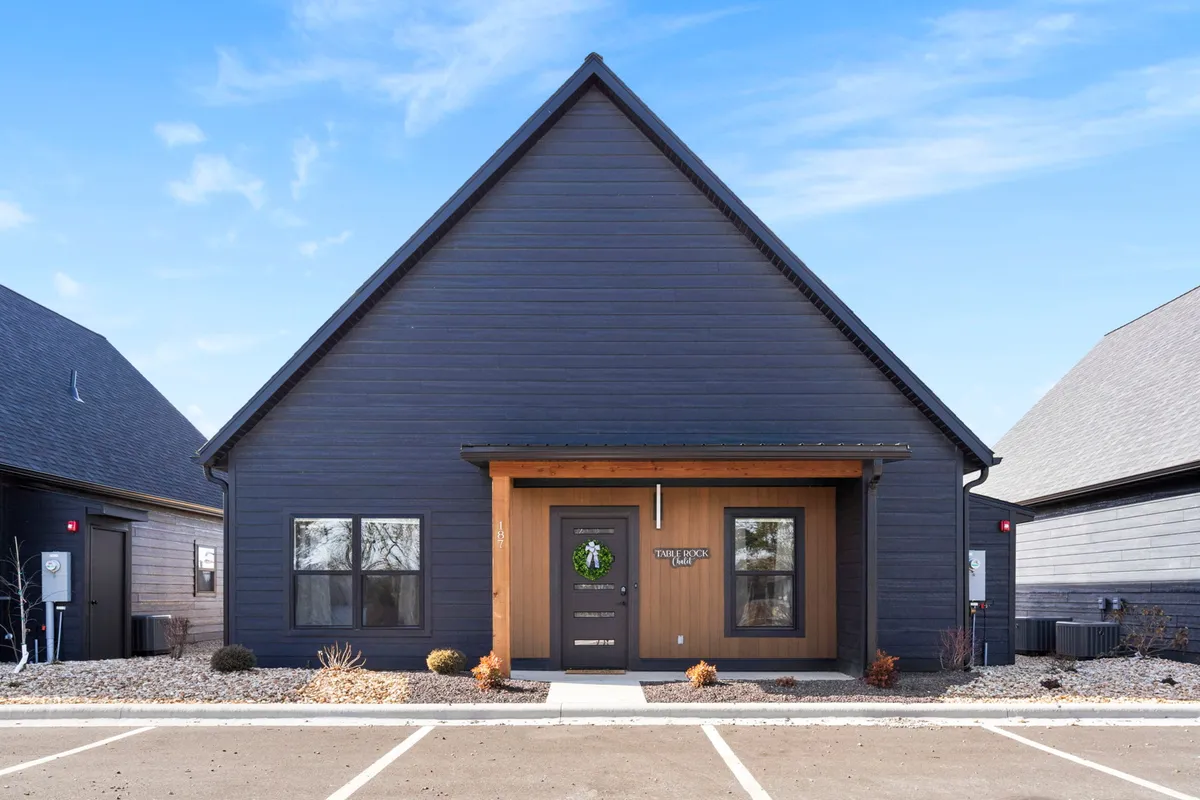 A welcoming exterior shot of the chalet’s main entrance, featuring a wooden porch, large windows, and a landscaped front yard. The inviting atmosphere hints at both privacy and the convenience of coming and going for local adventures.