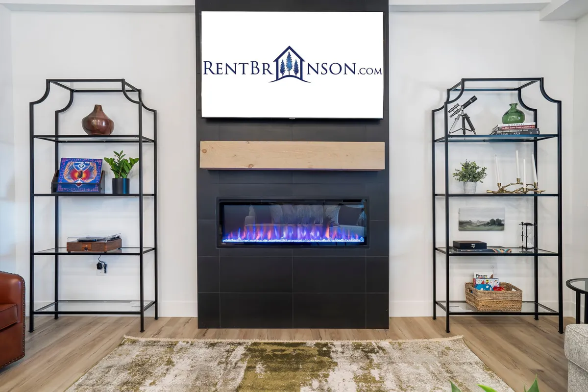 A cozy corner of the living area with an electric fireplace, decorative shelving, and a television. The setup is perfect for relaxed evenings watching movies or sharing stories by the fire.