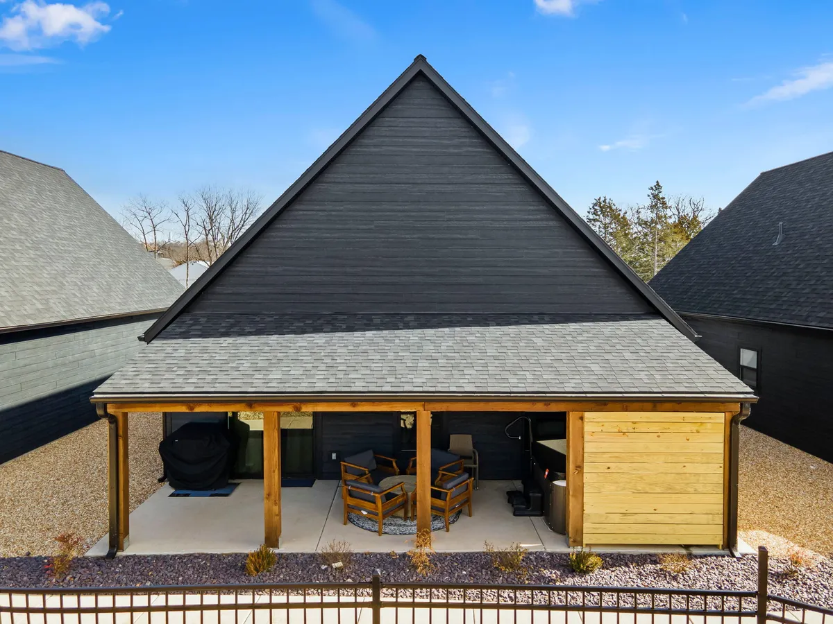 A tranquil exterior view of a private outdoor seating area that includes a hot tub, wooden porch, comfortable chairs, and gentle gravel landscaping. The scene blends comfort with scenic outdoor enjoyment, ideal for relaxation after exploring the local attractions.